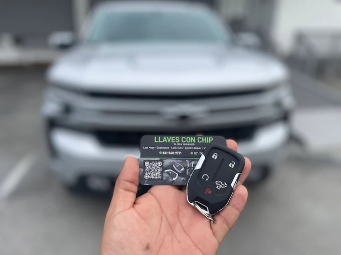 Hand holding car key fob with blurred vehicle in background