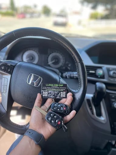 Hand holding Honda car keys and remote inside vehicle dashboard