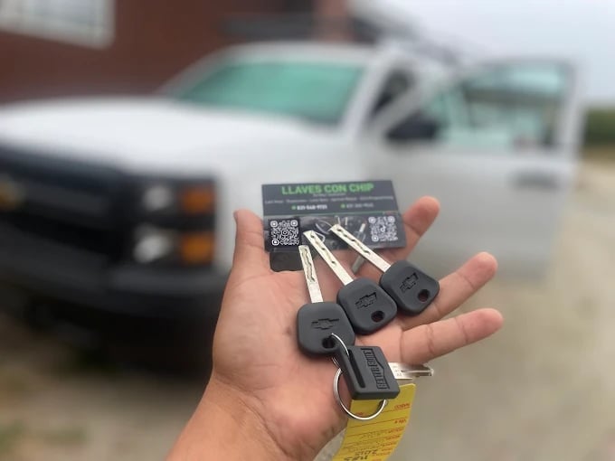 Hand holding car keys with vehicle in background