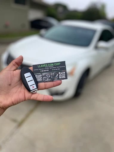 Hand holding car key card with white car in background