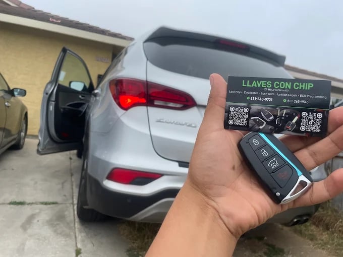 Hand holding car key with QR code and silver car in background