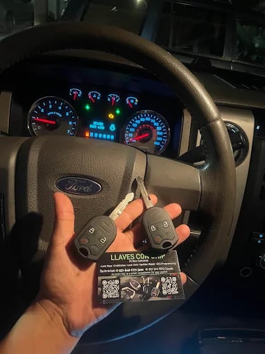 Hand holding car keys with Ford dashboard and instrument cluster in background