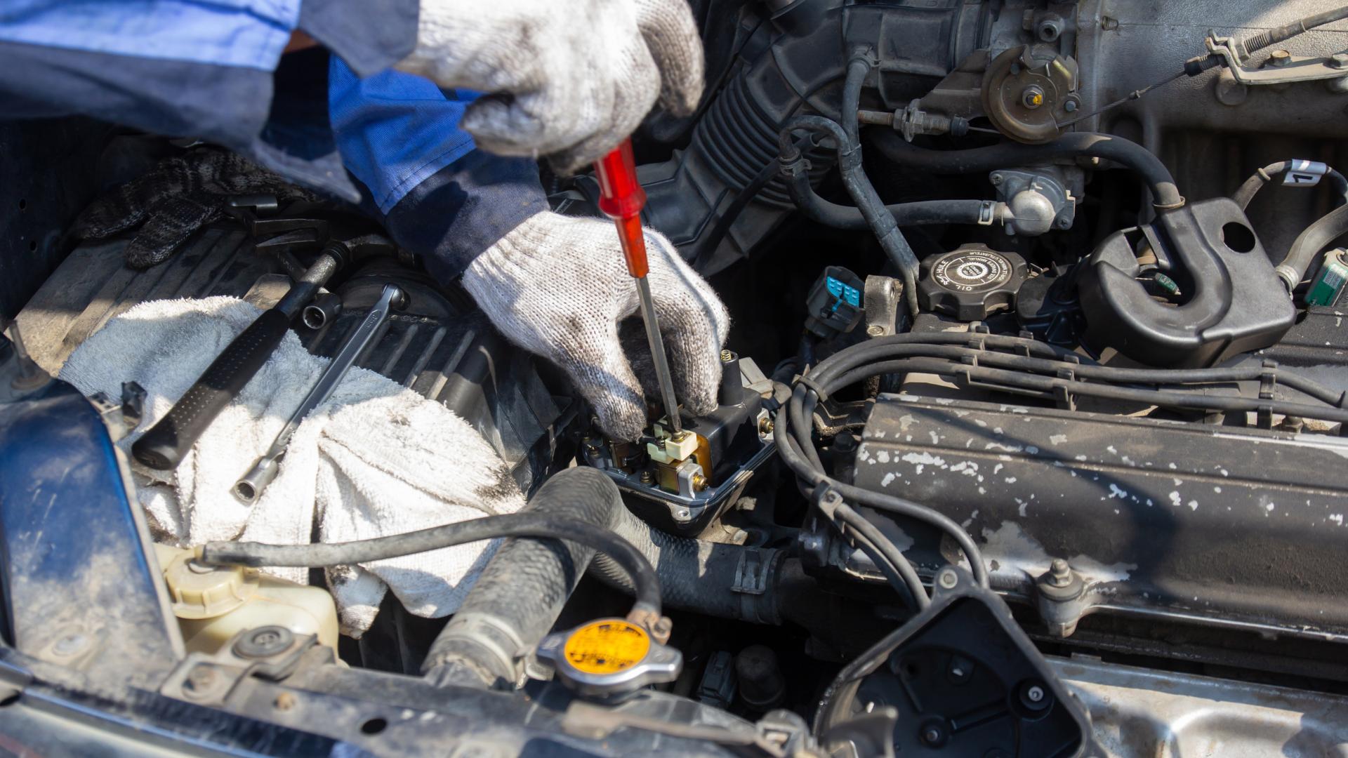 Mechanic working on vehicle engine wiring during ignition repair